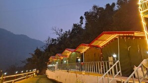 A row of tents with metal railings, set against a mountainous backdrop. - Haveli Resort Shivpuri (Rishikesh)