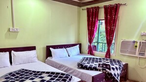 A room with two beds, a window with red curtains, a wall-mounted air conditioner, and a patterned blanket on one bed. - Haveli Resort Shivpuri (Rishikesh)