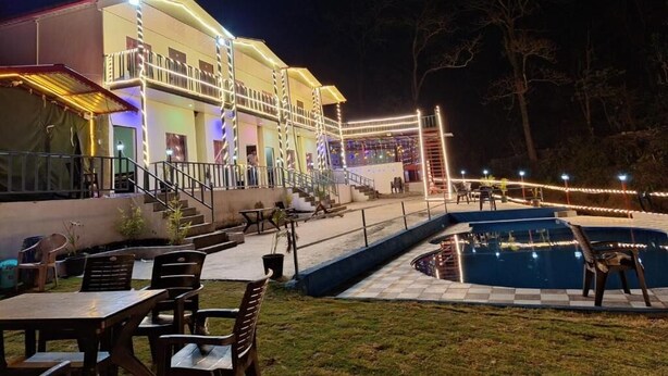 A hotel with outdoor seating, a pool, and a staircase leading to the upper floor. - Haveli Resort Shivpuri (Rishikesh)