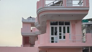 Un edificio rosa de varios pisos con balcones, un corredor cubierto y una escalera visible.