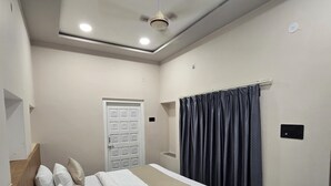 Un dormitorio con cama, ventilador de techo, una puerta y ventana con cortinas.
