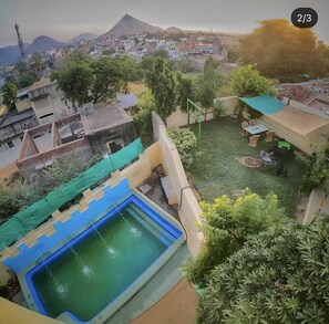 A residential area with a swimming pool, a green tarp, and a hose. - Hotel Shri Palace By Taaraa Hospitality (Pushkar)