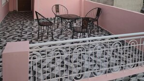 Un edificio rosa con balcón, una mesa con sillas y un suelo con diseño.