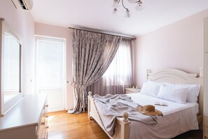 A bedroom with a bed, a nightstand, a dresser, a window with blinds, and a curtain. - Villa Ioannis (Mandra Eidyllia)