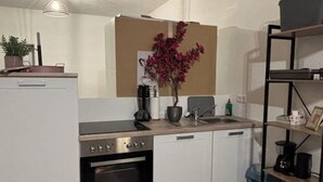 A compact kitchen with white cabinetry, a built-in oven, a sink, and a small countertop. - Emsquartier 2 (Emsdetten)