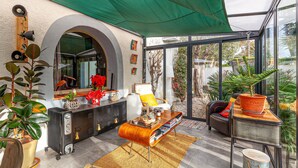 A modern living room with a large arched window, a green canopy, and various plants. - Awesome home in Six-Fours-les-Plages (Six-Fours-les-Plages)