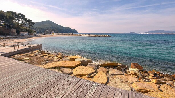 A coastal walkway with a wooden deck, rocky shoreline, and a view of the sea and distant cityscape. - Awesome home in Six-Fours-les-Plages (Six-Fours-les-Plages)