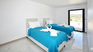 A hotel room with two beds, each with a blue bedspread and white pillows. There are white towels arranged on the beds, and a heart-shaped towel on the floor. - Villa avec piscine privée (Portel des Corbières)