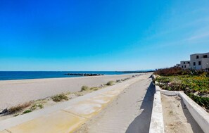 Een kustweg met een strand aan de ene kant en een rij moderne gebouwen aan de andere kant.