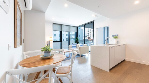 A modern kitchen with a central island, white cabinetry, and a large window offering a view of the city. - Preston Rooftop Oasis - Pool, Views & City Access (Preston)