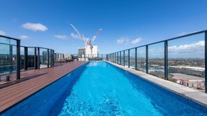 A rooftop swimming pool with a clear view of the cityscape and a construction crane in the background. - Preston Rooftop Oasis - Pool, Views & City Access (Preston)