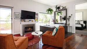 Una sala de estar moderna con chimenea, televisor y un área de descanso con alfombra roja.