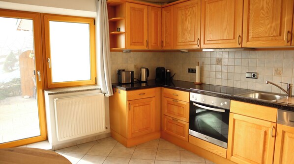 A kitchen with wooden cabinets, a built-in oven, and a window with curtains.