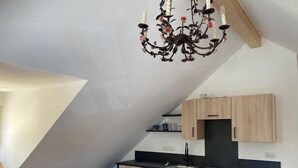 A modern kitchen with wooden cabinets, a black countertop, and a chandelier. - Vacation apartment Kunterbunt (Bad Reichenhall)