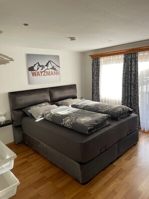 A modern bedroom with a large bed, a headboard, a bedside table, and a wall-mounted artwork. - Apartment Lukas 108 sqm for 2 to 5 persons with balcony (Schönau am Königssee)