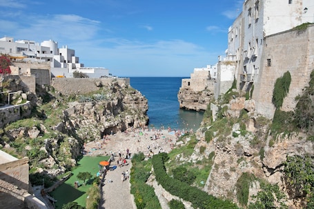 A coastal town with a rocky beach, white buildings, and a clear blue sky.