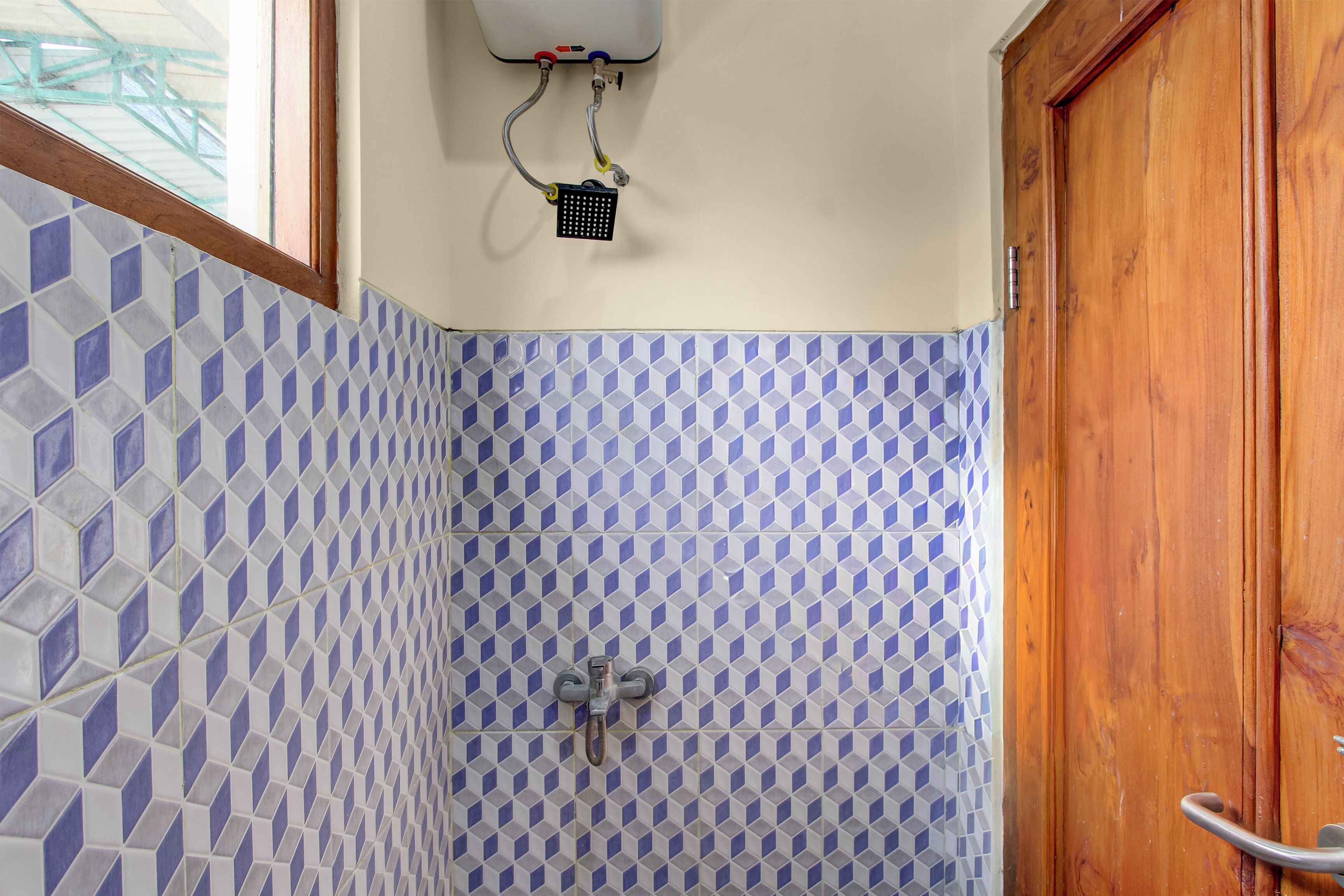Une salle de bain avec une douche, des murs carrelés et une porte en bois.