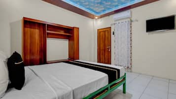 Un dormitorio con cama, armario de madera y televisor en la pared.