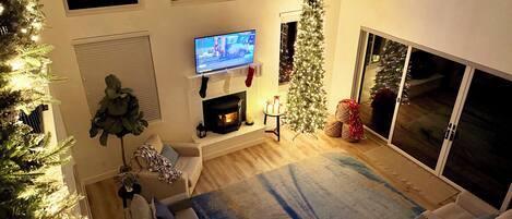 Ein Wohnzimmer mit Kamin, Fernseher, Weihnachtsbaum und einer Couch.