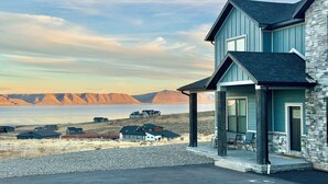 A modern two-story house with a stone facade and a covered porch. - Luxury Home at Bear Lake! Sleeps 30! Resort Hot Tub! Tesla Charging! (Fish Haven)