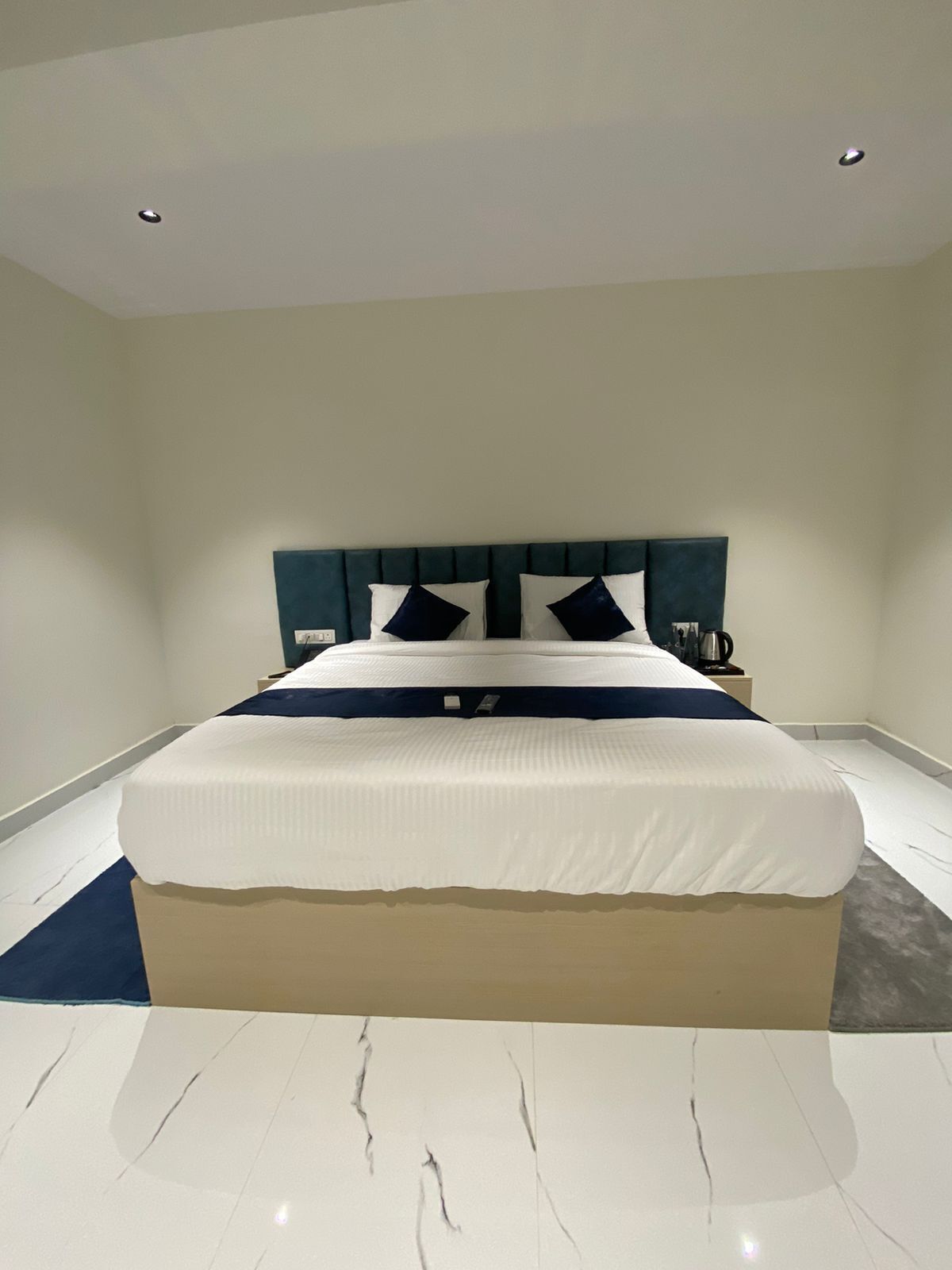A modern bedroom with a large bed, a headboard, and a nightstand.
