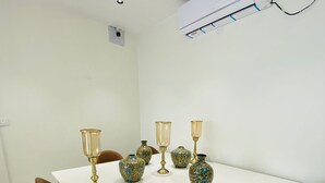 A white dining table with six brown chairs, surrounded by decorative vases and candle holders. - Dreamscape Hotel by Fracspace  OU Colony (Hyderabad)