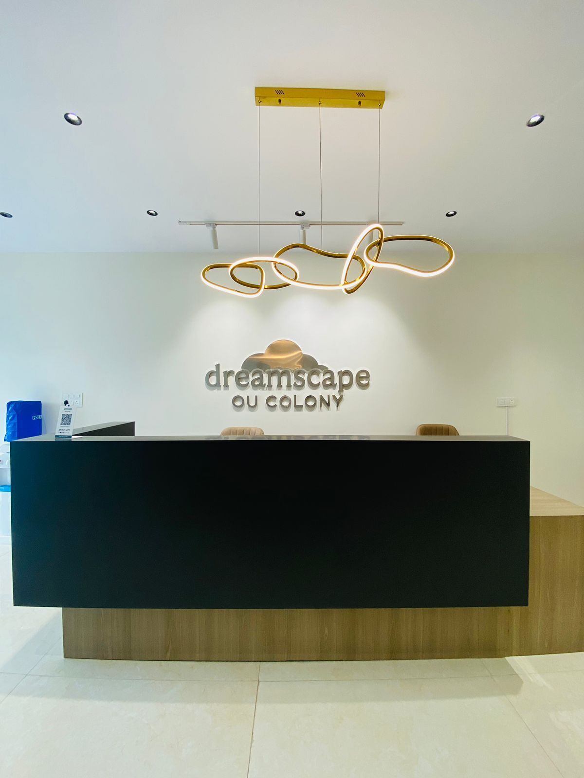 Un comptoir d’accueil au design moderne, orné d’un logo sur lequel on peut lire « dreamscape OU COLONY ».