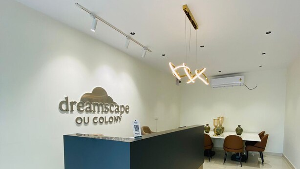 A reception area with a modern desk, chairs, and a dining table with chairs. - Dreamscape Hotel by Fracspace  OU Colony (Hyderabad)