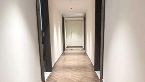 A long, narrow hallway with a herringbone-patterned floor and white walls. - Dreamscape Hotel by Fracspace  OU Colony (Hyderabad)