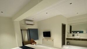 A modern hotel room with a bed, a TV, a bathroom with a mirror, and a door leading to another room. - Dreamscape Hotel by Fracspace  OU Colony (Hyderabad)