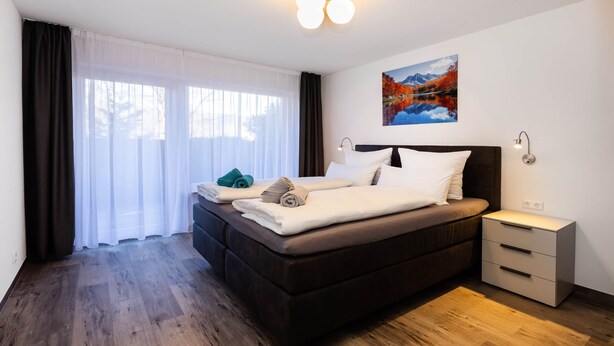 Una habitación de hotel moderna con una cama grande, una mesita de noche y un cuadro en la pared.