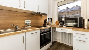 Una cocina moderna con armarios blancos, encimera de madera, horno empotrado, microondas y cafetera.