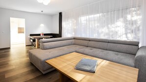 Una sala moderna con un sofá seccional, una mesa de centro de madera y un comedor al fondo.
