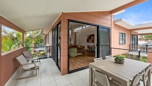 A modern apartment with a balcony, a dining area, and a living room with a sofa and a TV. - Byron Bay Accom - Keesing Villa 8 right in the heart of Byron Bay (Byron Bay)