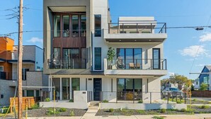 Et moderne hus i to etager med store vinduer, en balkon og et lille haveområde.