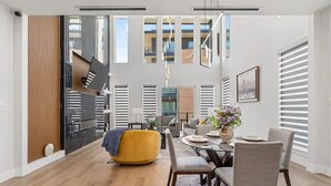 En moderne stue med et glasbord, behagelige møbler og et stort vindue med persienner.