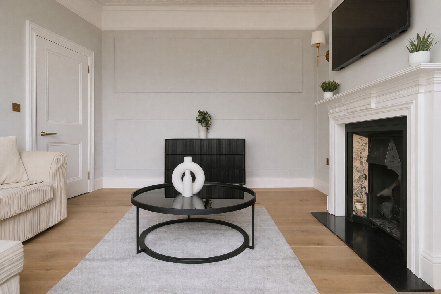 A living room with a sofa, a coffee table, a fireplace, and a television mounted on the wall.