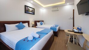 A hotel room with two beds, a desk with a chair, a TV, and an air conditioning unit. - Hoi An Impression Homestay (Hoi An)