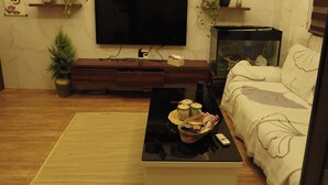 Olohuone, jossa on litteänäyttöinen televisio, puinen mediakeskus, sohva, sohvapöytä ja koriste-esineitä.