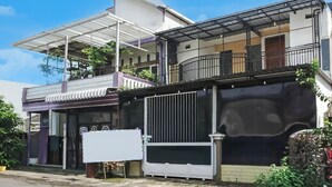Un edificio de dos pisos con un balcón, un porche cubierto y un gran portón negro.