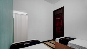 Una habitación con dos camas individuales, un armario de madera, una puerta con cortina roja y una ventana con persianas blancas.