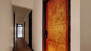 Un pasillo con una puerta de madera a la derecha y un ventanal al final.