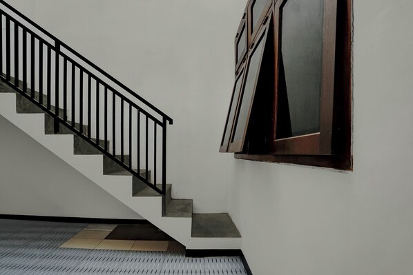 A staircase with a black railing leading to a landing. - OYO 95035 Harmony Guest House Syariah (Malang)
