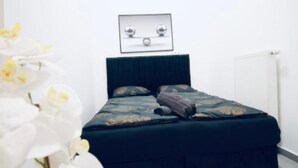 Een slaapkamer met een bed, een donkere hoofdbord en een ingelijst beeld boven het bed.