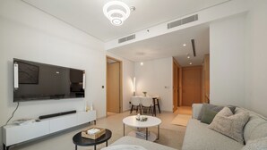 Ein modernes Wohnzimmer mit Flachbildfernseher, einer Couch, einem Couchtisch und einem Essbereich mit Tisch und Stühlen.