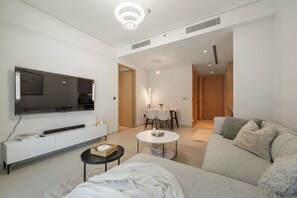 Ein modernes Wohnzimmer mit Flachbildfernseher, einer Couch, einem Couchtisch und einem Essbereich mit Tisch und Stühlen.