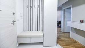 Et moderne, minimalistisk værelse med en indbygget bænk, et garderobeskab med lodrette håndtag og et lille bord med en stol.