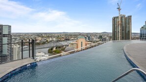 Ein Pool auf dem Dach mit Blick auf die Stadt, eine Brücke und ein Baukran.