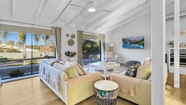 A spacious living room with a large window, a ceiling fan, and a view of the outside. - Pet-friendly Private Retreat with Large Backyard (Surf Beach)