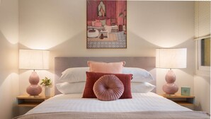 A neatly made bed with a headboard, two bedside tables with lamps, and a painting above the bed. - Cosy 2-Bed Apartment in the Heart of Strathfield (Strathfield)